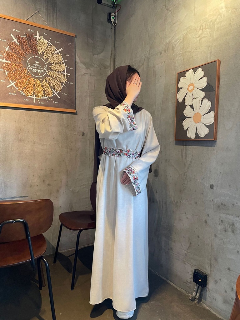 An elegant and modern lined linen dress adorned with embroidery and a belt