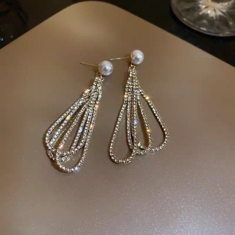 Elegant earrings featuring a drop shape, adorned with full diamonds and pearls, complemented by long tassels for a luxurious and sophisticated look