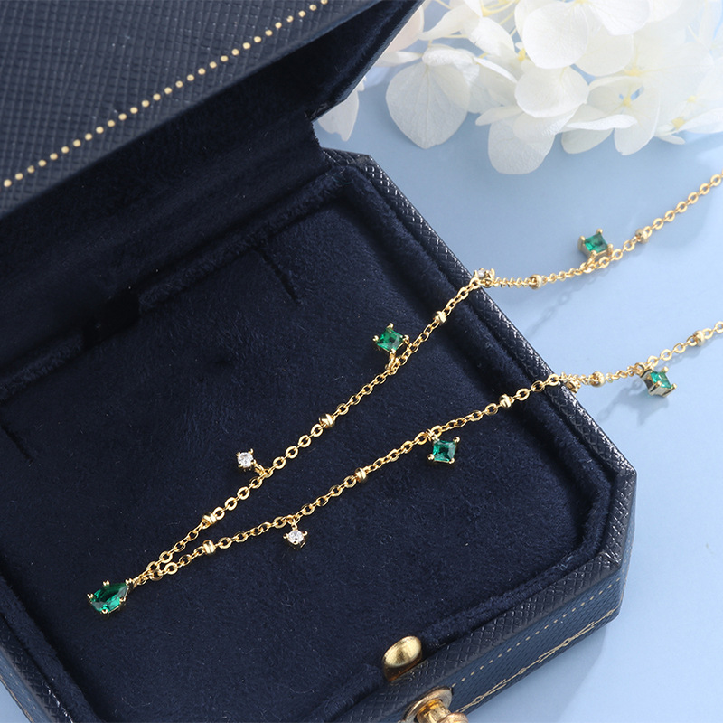 A stunning necklace featuring a water drop design adorned with emerald and zircon stones, perfect for adding a touch of luxury and elegance to your look